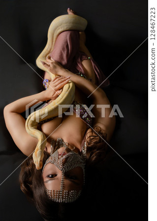 Woman elegantly poses with a snake in a studio setting 128467223