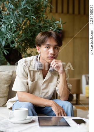 Handsome person looking at camera in coffee shop Handsome person looking at camera in coffee shop 128468023