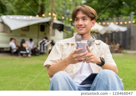 Young non binary person having road trip and camping with friends in nature using phone Young non binary person having road trip and camping with friends in nature using phone 128468047