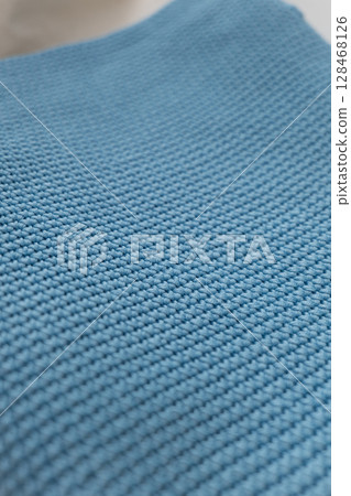 Textured blue fabric displayed on a surface in natural light showcasing its intricate weave pattern 128468126
