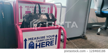 Person fitting bag into airport baggage sizer (pink frame). Carry-On Bag Airport Sizer Check - Travel Essentials, Hand Luggage, Budget Airline Rules Person fitting bag into airport baggage sizer (pink frame). Carry-On Bag Airport Sizer Check - Travel Essentials, Hand Luggage, Budget Airline Rules 128468186