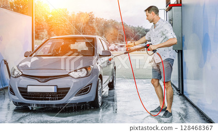 Car cleaning. Man washing car with spray. Foam water soap self service. 128468367