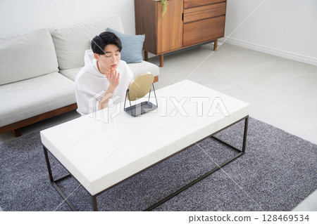 A man checking his skin care in the mirror. The reflection of his face in the mirror creates a bright, clean, and lively image. 128469534