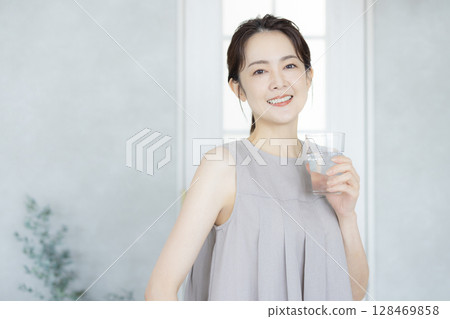 Middle-aged woman drinking water in the kitchen 128469858