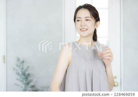 Middle-aged woman drinking water in the kitchen 128469859