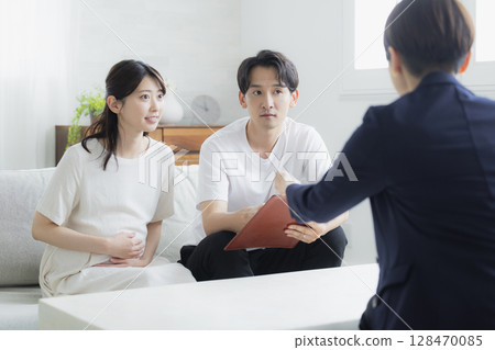 一對夫婦正在與一位西裝革履的女士進行諮詢 一對夫婦正在與一位西裝革履的女士進行諮詢 128470085