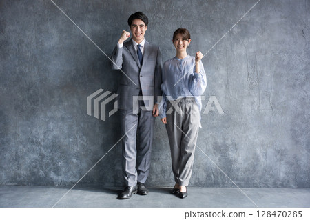Full body of business men and women in suits on a gray background, fist pump, looking at camera Full body of business men and women in suits on a gray background, fist pump, looking at camera 128470285