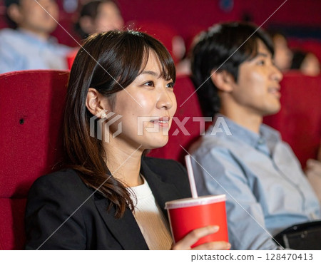 AI-generated image of a Japanese woman enjoying watching a movie at a movie theater 128470413