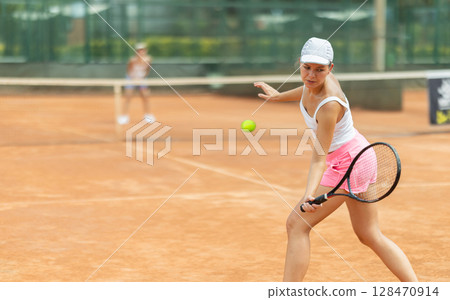 Woman playing tennis against female opponent on tennis court Woman playing tennis against female opponent on tennis court 128470914