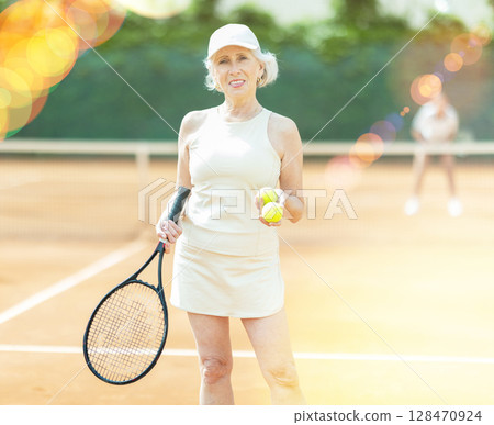 Elderly woman posing on tennis court Elderly woman posing on tennis court 128470924