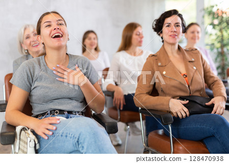small group of women are sitting in audience, listening to lecture and laugh at amusing case 128470938