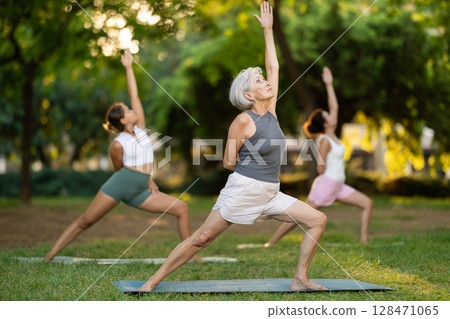 Elderly woman doing yoga in warrior pose Elderly woman doing yoga in warrior pose 128471065