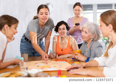 Group of cheerful female colleagues playing board game in office 128471071