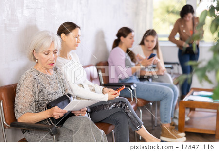 Elderly woman with documents waiting for her turn on chair Elderly woman with documents waiting for her turn on chair 128471116