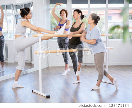 Group of women relax during training at barre Group of women relax during training at barre 128471184
