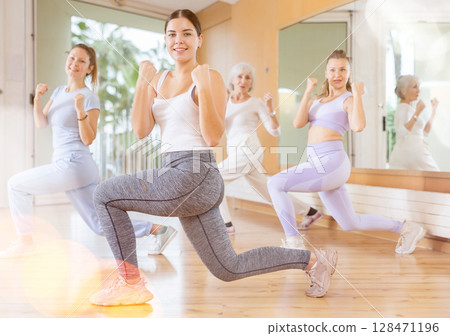Active young woman practicing aerobic dance in training hall 128471196