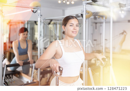 Young girl doing exercises on wunda chair in pilates studio Young girl doing exercises on wunda chair in pilates studio 128471223