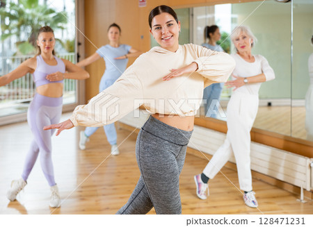 Excited positive women of different ages performing modern dancing exercises in school for adults Excited positive women of different ages performing modern dancing exercises in school for adults 128471231