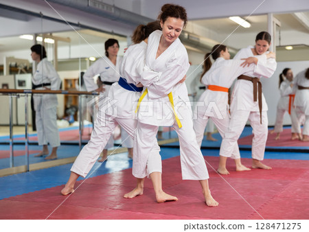 Women practice judo techniques in pairs Women practice judo techniques in pairs 128471275