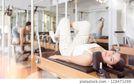 Concentrated young girl practicing exercises on Pilates reformer 128471299
