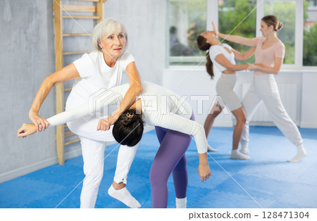 Young and elderly women training self-defense techniques 128471304