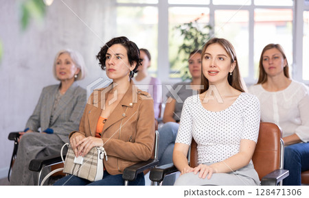 In audience, students sit staring at teacher and listen to lecture 128471306