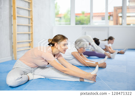 Group of women doing stretching in studio Group of women doing stretching in studio 128471322