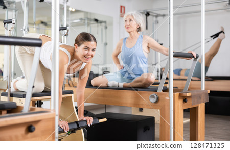 Young girl doing exercises on wunda chair in pilates studio Young girl doing exercises on wunda chair in pilates studio 128471325