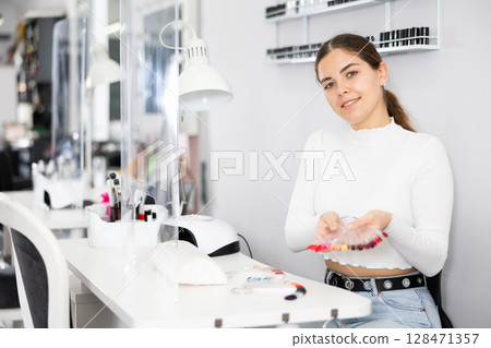 Manicurist demonstrating a palette with color schemes of nail polish 128471357