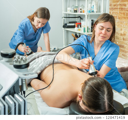 Professional cosmetologists performing electroporation procedure for female patient 128471419