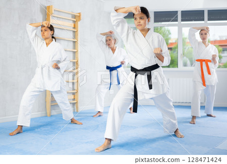Female martial arts instructor leading karate kata training for group 128471424
