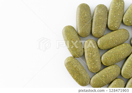 Multiple khaki supplement tablets (oval shaped) on a white background 128471903