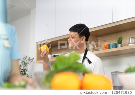 Healthy Lifestyle: Man Holding Fresh Yellow Bell Pepper in Kitchen Healthy Lifestyle: Man Holding Fresh Yellow Bell Pepper in Kitchen 128471980