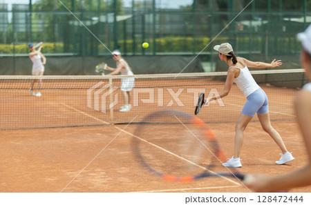 Woman playing tennis against female opponent on tennis court Woman playing tennis against female opponent on tennis court 128472444