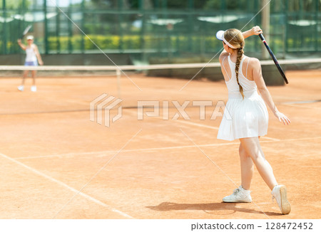 Female athlete plays tennis on open court 128472452