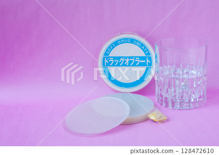 Medicinal wafer, a cup of water, and powdered medicine wrapped in the wafer 128472610