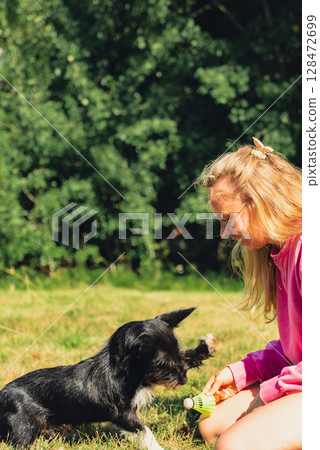 Young woman playing with her dog and shuttlecocks concept. Summer outdoor activities. Staycation leisure time. Petrenthood pet love Young woman playing with her dog and shuttlecocks concept. Summer outdoor activities. Staycation leisure time. Petrenthood pet love 128472699