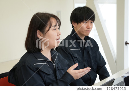 資深工程師指導初級工程師穿著工作服 資深工程師指導初級工程師穿著工作服 128473913