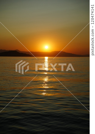 Tranquil Ocean Sunset with Reflective Waters 128474141