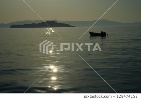 Solitary Boat at Sunset on Calm Sea Solitary Boat at Sunset on Calm Sea 128474152