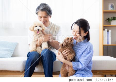 A middle-aged couple spending time with their dog in the living room A middle-aged couple spending time with their dog in the living room 128474167
