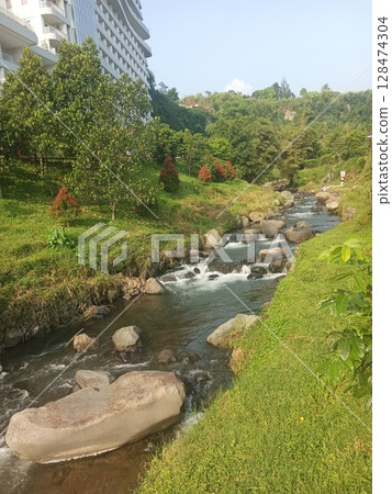 scenic river flowing through a lush green landscape with rock and trees scenic river flowing through a lush green landscape with rock and trees 128474304