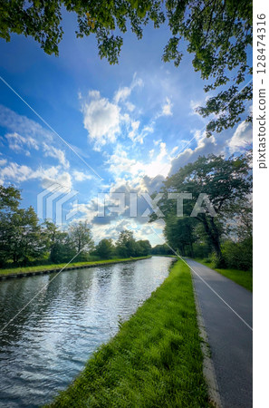 A Peaceful and Serene River Pathway Stretching Out Set Against a Stunning and Expansive Sky 128474316