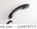 Black analog handset receiver with curly cord on white background. 128474773