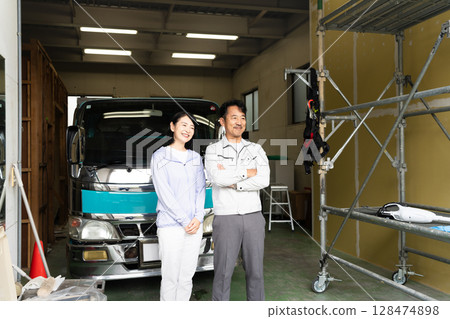 Middle-aged man and woman posing in front of a truck Construction image Middle-aged man and woman posing in front of a truck Construction image 128474898