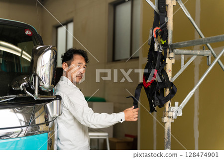 一名中年男子在卡車前擺姿勢的施工影像 一名中年男子在卡車前擺姿勢的施工影像 128474901