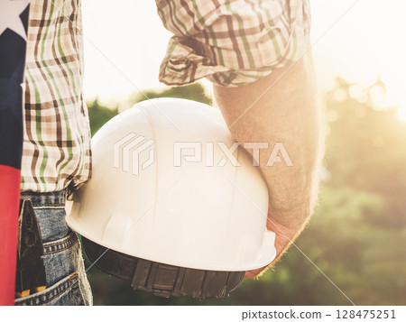 Attractive man in work clothes, holding American Flag Attractive man in work clothes, holding American Flag 128475251