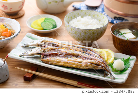Steaming Japanese breakfast: Grilled fish (filleted saury), rice and miso soup on a table 128475882