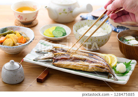 Steaming Japanese breakfast: Grilled fish (filleted saury), rice and miso soup on a table 128475885