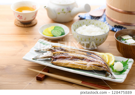 Steaming Japanese breakfast: Grilled fish (filleted saury), rice and miso soup on a table 128475889
